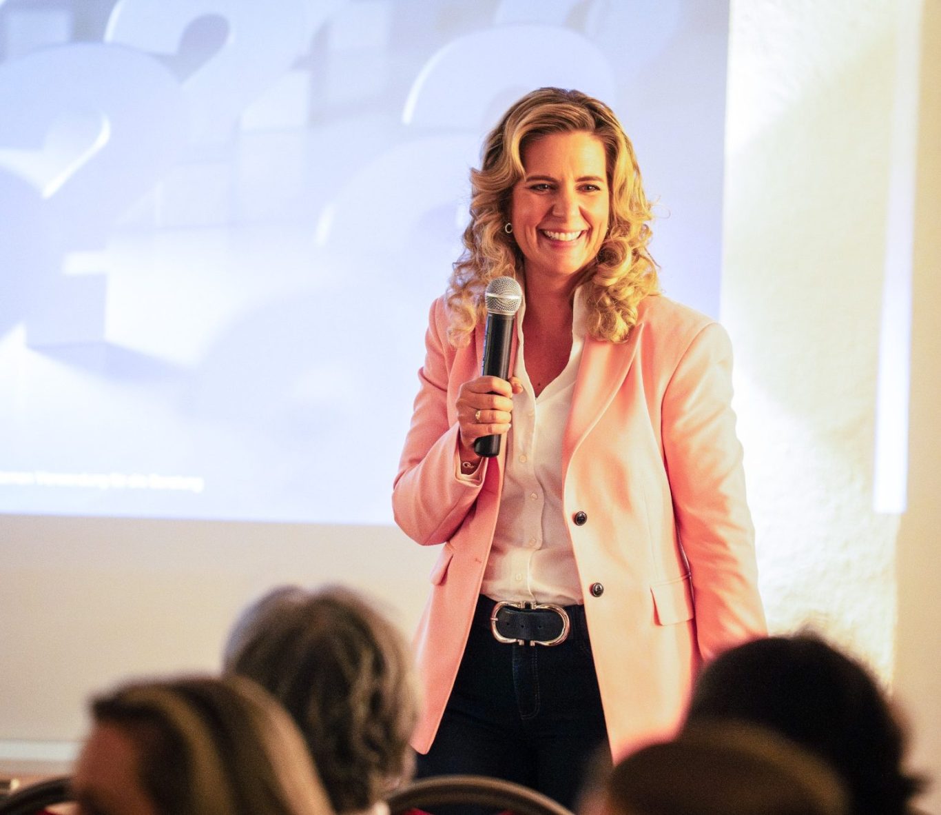 Natascha Enders lächelt im schwarzen Blazer, lehnt an einer Betonwand – Teaser zur Keynote Female Finance